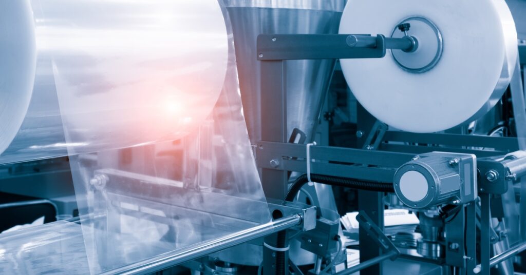A close-up of the roller of the plastic bag production machine in a factory in the light blue scene.