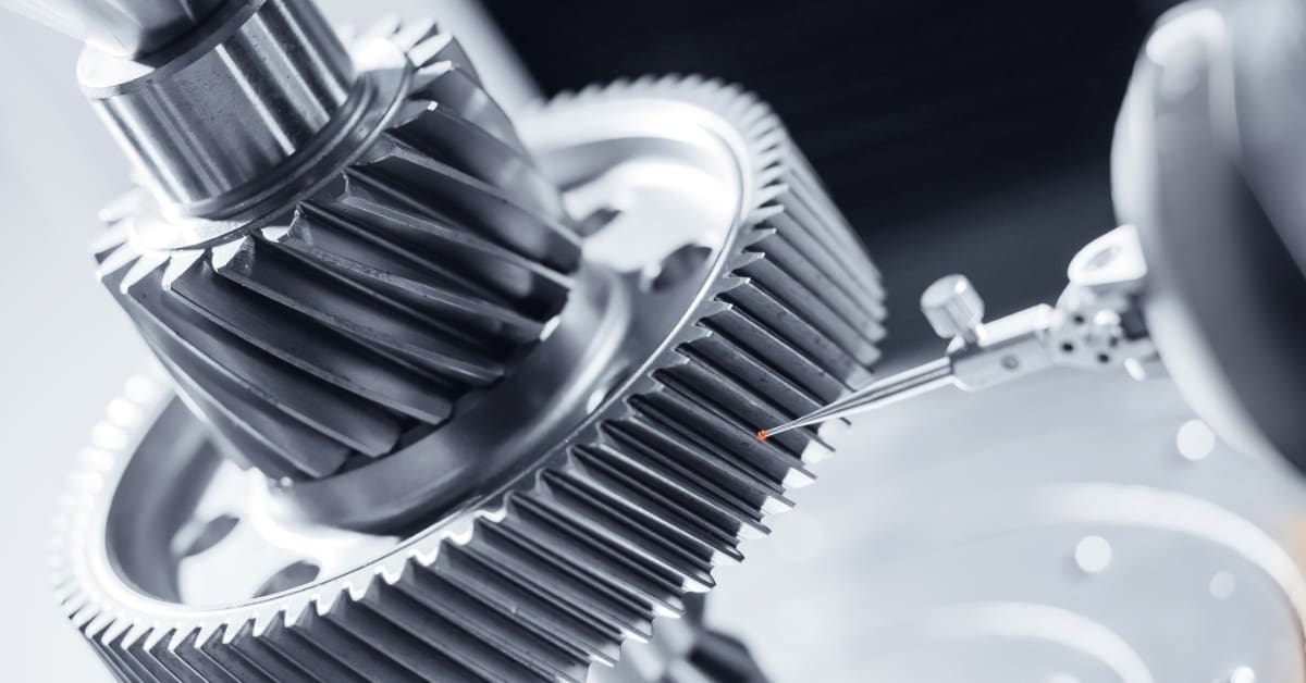 Precision probe inspects the teeth of large interlocking steel gears in a close-up of mechanical components